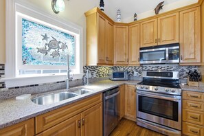 A kitchen with wooden cabinets, a stainless steel sink, a dishwasher, a microwave, a stove, and a toaster.