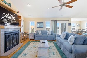 Ein Wohnzimmer mit Kamin, Deckenventilator und großem Fenster.