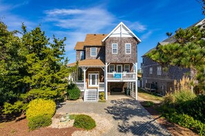 A two-story wooden house with a porch, a mailbox, and a sign indicating a vacation rental.