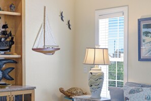 A room with a sailboat model, a lamp, and a window with blinds.