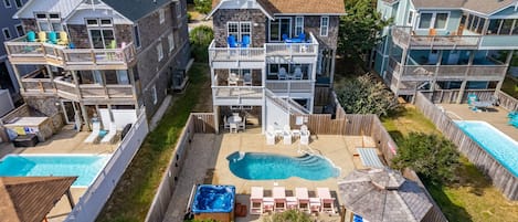 Un edificio residencial de varios pisos con piscina en el patio, mobiliario exterior y un jacuzzi.