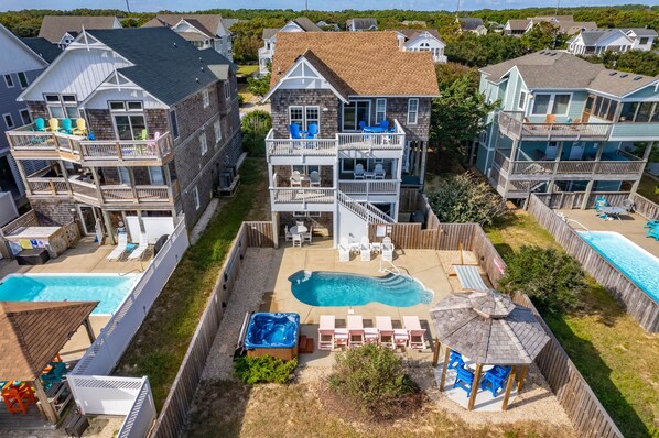 A multi-story residential building with a backyard pool, outdoor seating, and a hot tub.