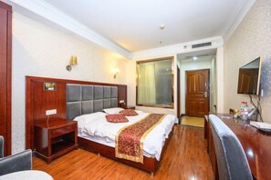 Habitación de hotel con una cama grande, una mesita de noche, un escritorio y una televisión.