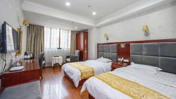 A hotel room with two beds, a desk, a chair, a TV, and a window with curtains.