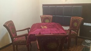 A dining area with a table covered by a red cloth, surrounded by four chairs with floral patterns. - Nanjiang Shuangyu Holiday Hotel (Nanjiang)