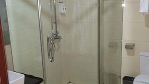 A glass-enclosed shower stall with a handheld showerhead, a toilet, and a trash bin. - Nanjiang Shuangyu Holiday Hotel (Nanjiang)