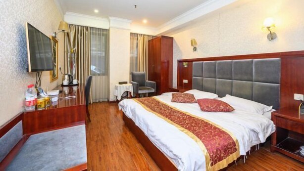 A hotel room with a bed, a desk, a chair, a television, and a window with curtains. - Nanjiang Shuangyu Holiday Hotel (Nanjiang)