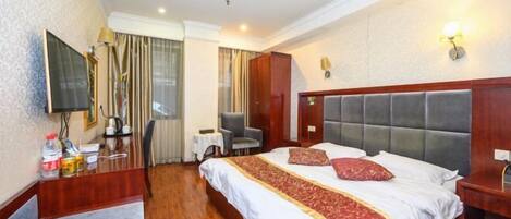 A hotel room with a bed, a desk, a chair, a television, and a window with curtains.