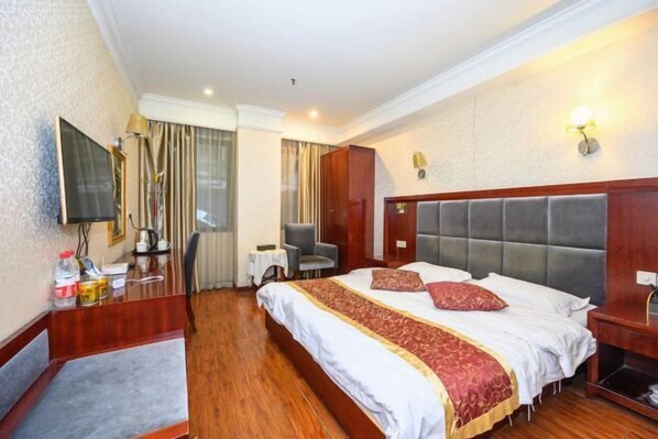 Una habitación de hotel con una cama, un escritorio, una silla, un televisor y una ventana con cortinas.