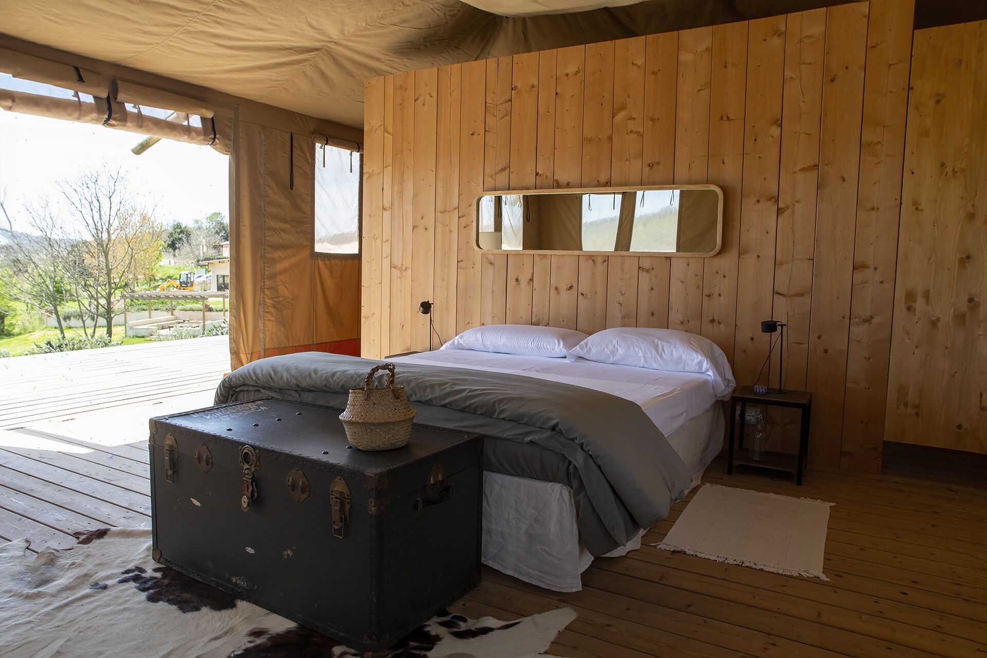 Camera da letto con pannelli in legno, un letto, un comodino e una valigia.