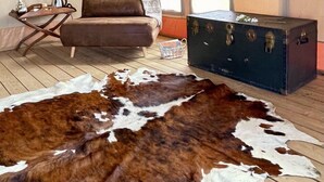 A tented room with a leather sofa, a trunk, and a cowhide rug. - Tenuta San Lodovico (Scansano)
