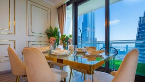 Un'area pranzo moderna con tavolo in vetro, sedie dorate e vista sulla città.