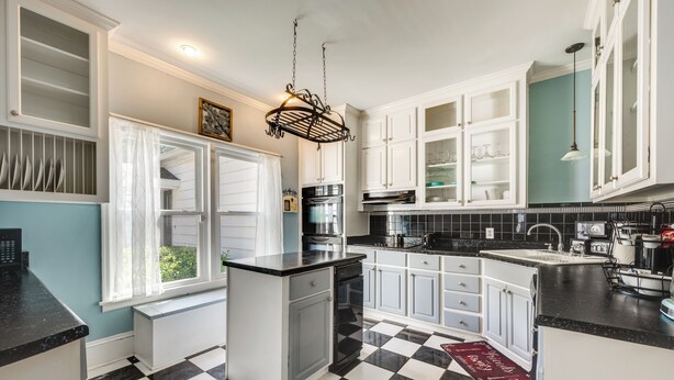 A kitchen with white cabinets, black countertops, and a checkered floor. - Pet-Friendly Fort Valley Home w/ Private Pool (Fort Valley)
