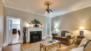 A living room with a fireplace, a sofa, a coffee table, and a chandelier. - Pet-Friendly Fort Valley Home w/ Private Pool (Fort Valley)