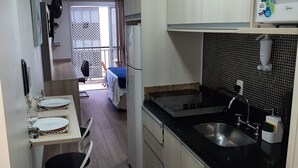 Una cocina compacta con fregadero, estufa y comedor.