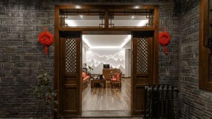 A traditional wooden entrance with a modern interior featuring a sofa and a table. - Wangjiang Shanju Guesthouse (Fenghuang County)