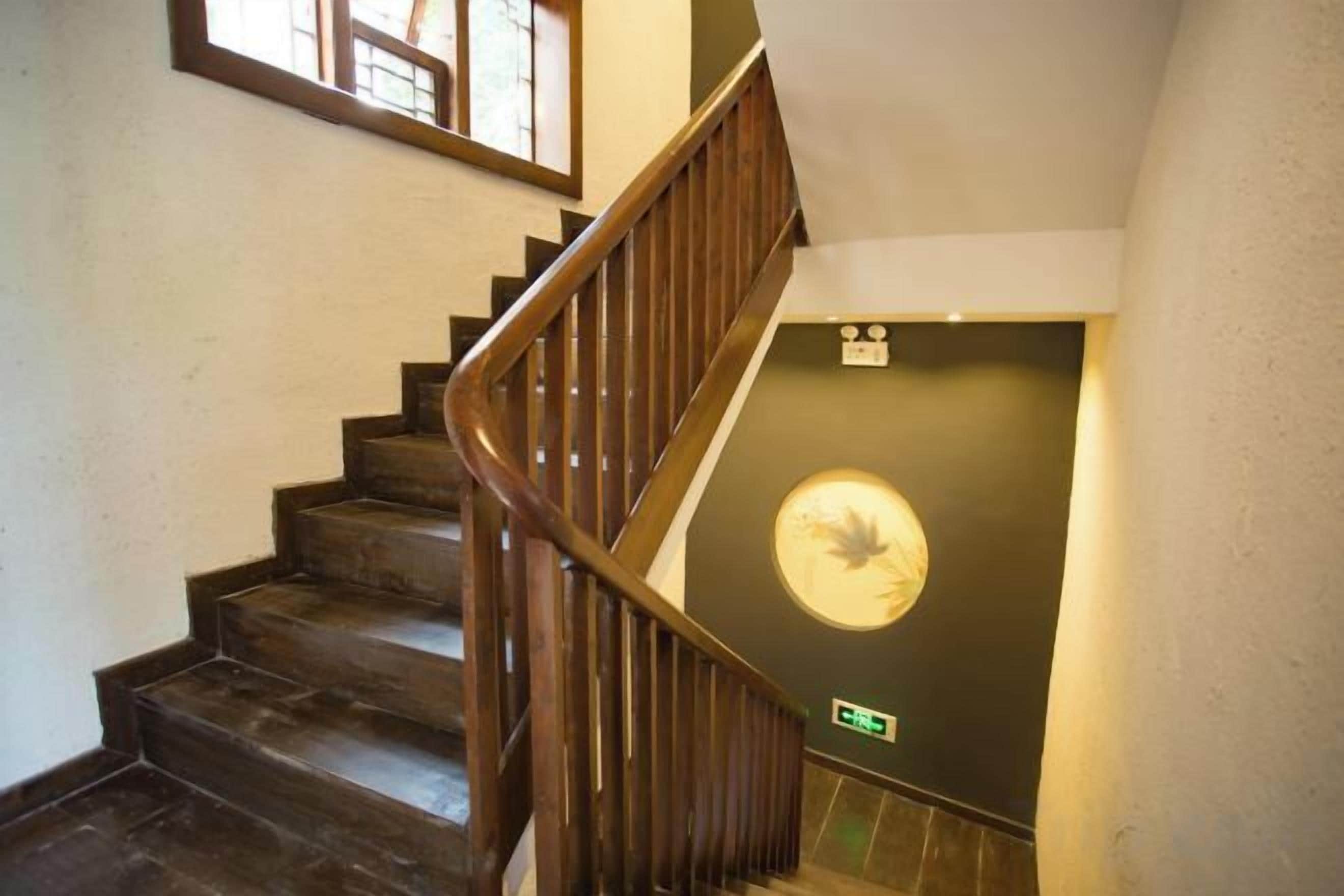 A wooden staircase with a handrail leading to a door with a circular emblem.