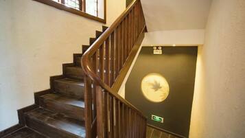 A wooden staircase with a handrail leading to a door with a circular emblem.