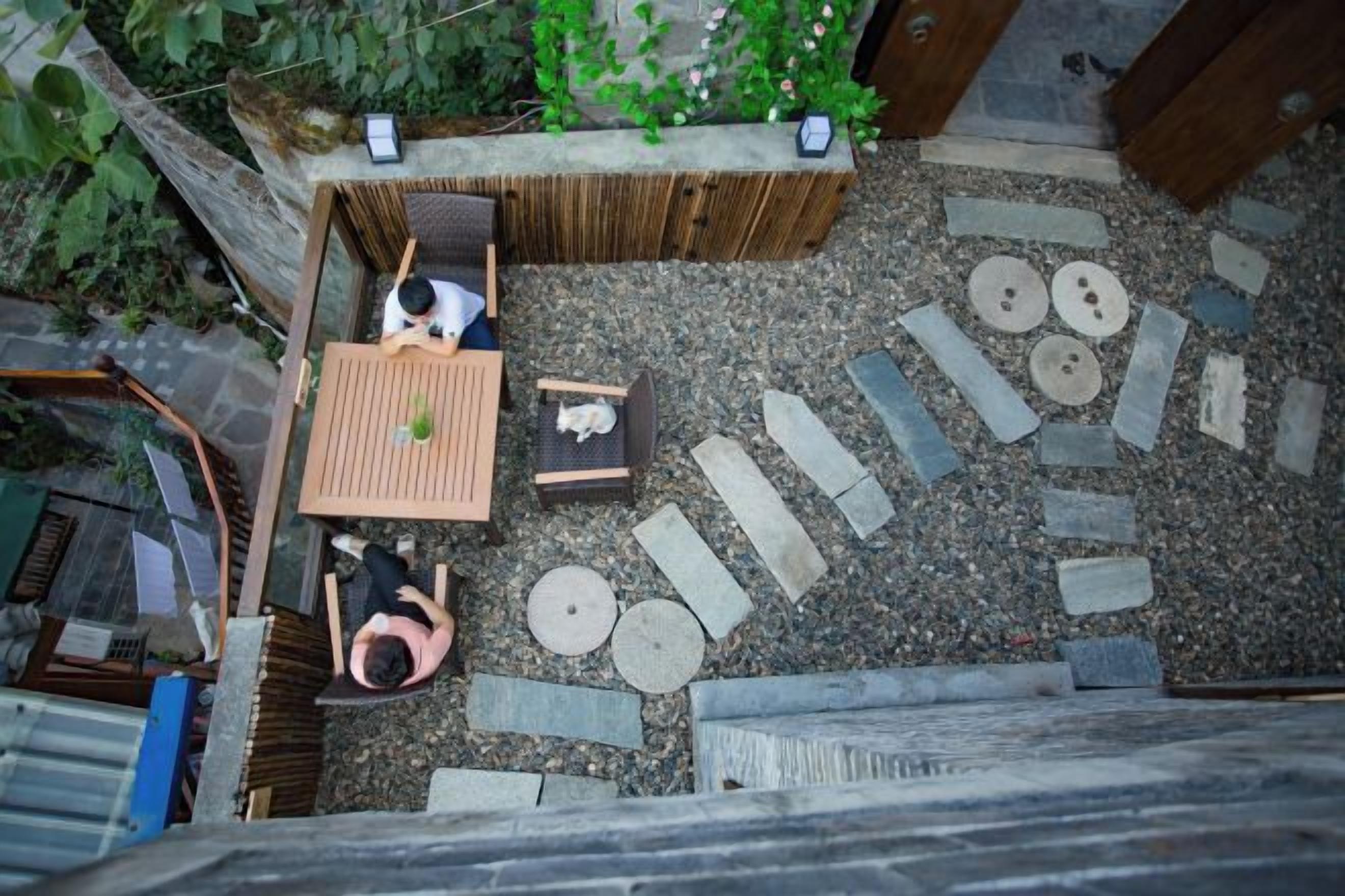 A rooftop garden with a wooden table, chairs, and a small seating area.