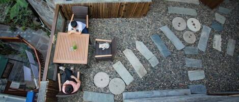 A rooftop garden with a wooden table, chairs, and a small seating area.