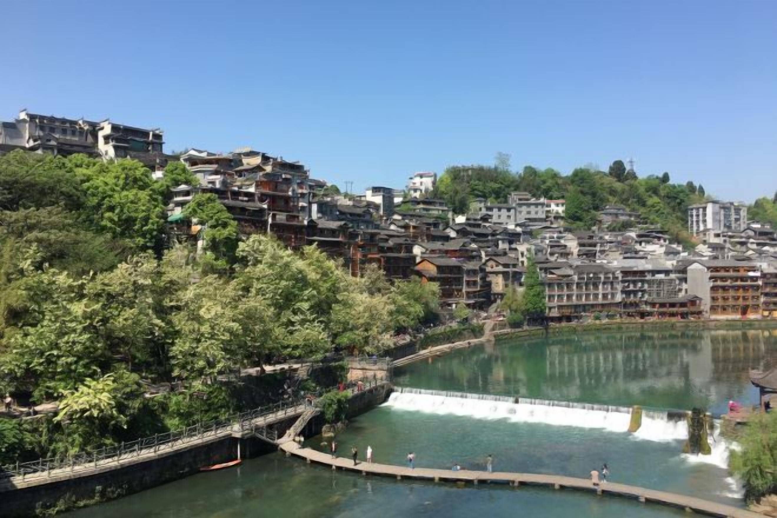 Une ville riveraine aux bâtiments traditionnels, avec un pont et un ciel dégagé.