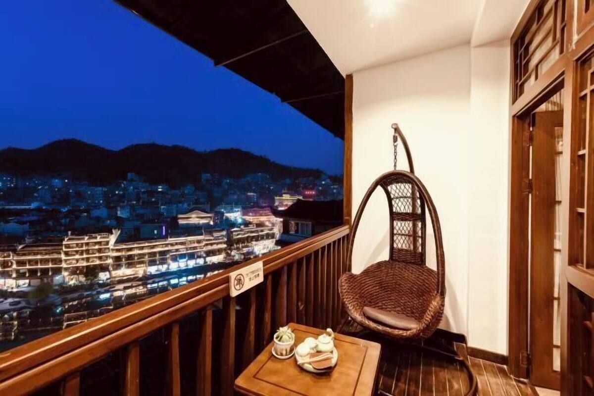Un balcon avec un fauteuil en osier et une petite table sur laquelle se trouvent une théière et des tasses.
