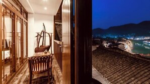 A balcony with a view of a river and city lights at night. - Wangjiang Shanju Guesthouse (Fenghuang County)