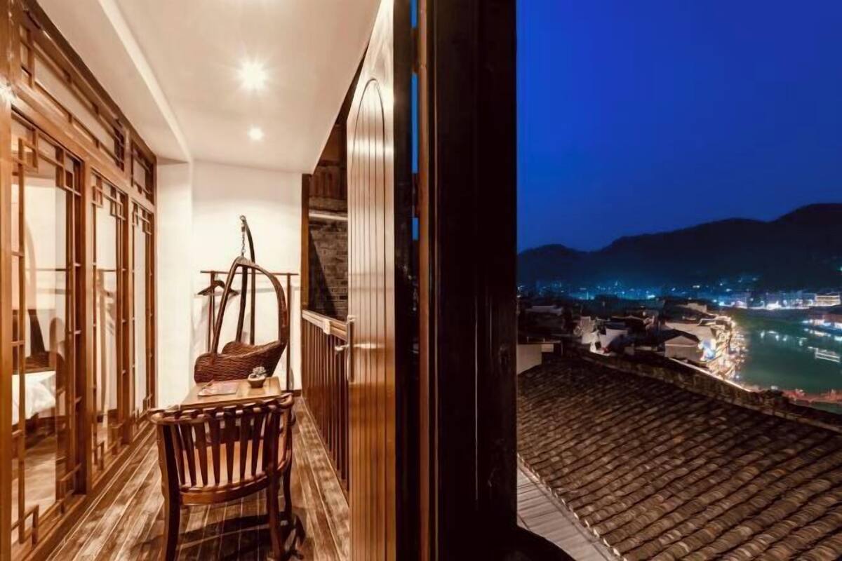 Un balcon avec vue sur une rivière et les lumières de la ville la nuit.