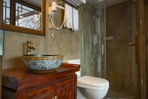 A bathroom with a large decorative bowl sink, a toilet, and a glass shower enclosure. - Wangjiang Shanju Guesthouse (Fenghuang County)
