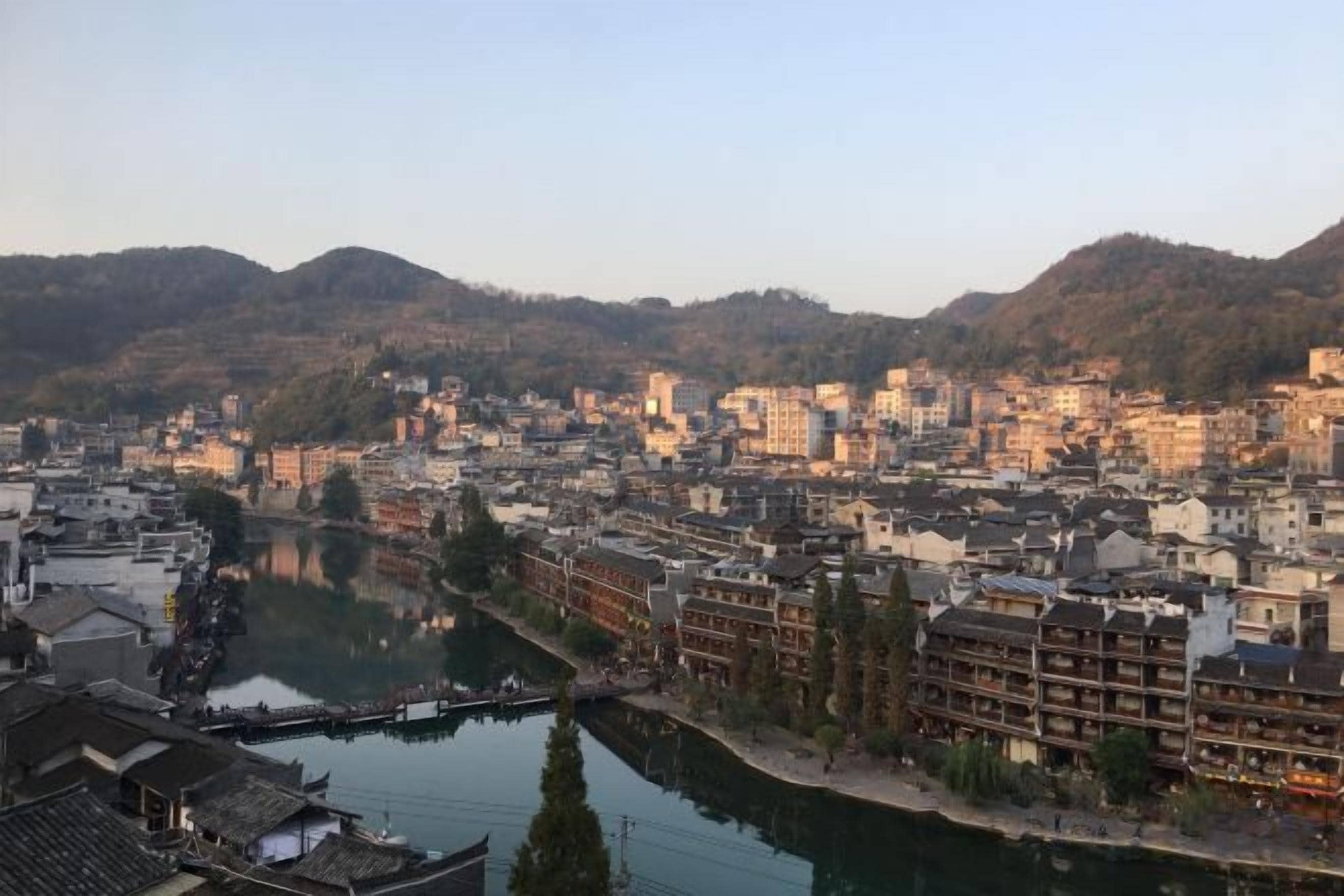 Une vue sur la ville, avec ses bâtiments aux architectures traditionnelles, le long d’une rivière paisible.