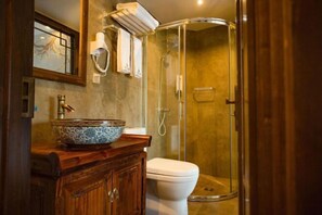 A bathroom with a glass shower enclosure, a white toilet, and a wooden vanity with a decorative bowl. - Wangjiang Shanju Guesthouse (Fenghuang County)