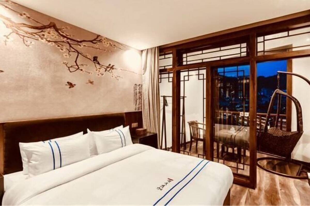 Une chambre d’hôtel avec un lit, une table de chevet, une chaise et un balcon avec vue.