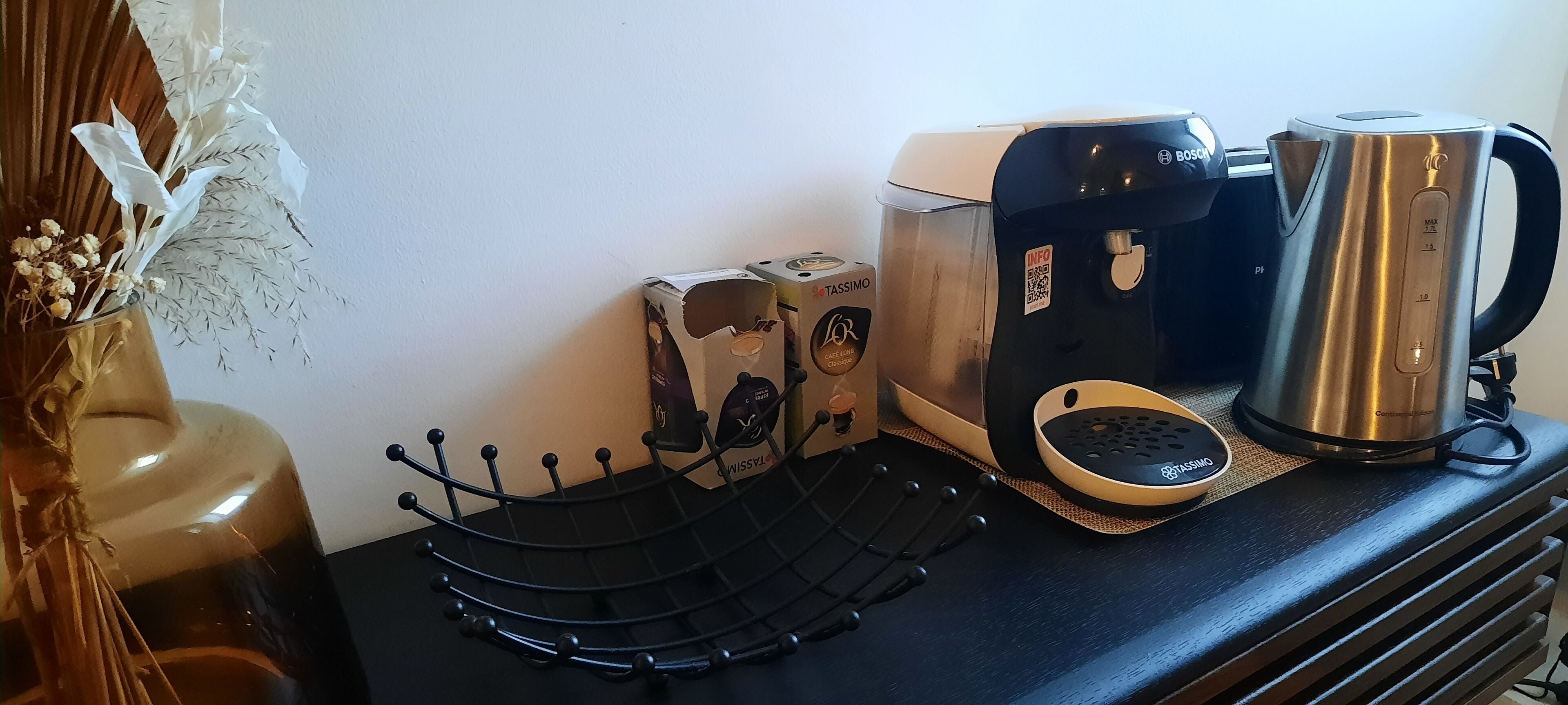 Una cafetera, un hervidor y un soporte para cápsulas de café sobre una encimera.