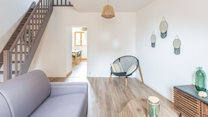 A modern living room with a staircase, a dining area, and a kitchen visible in the background. - Le Jaudy - Localisation idéale (Treguier)