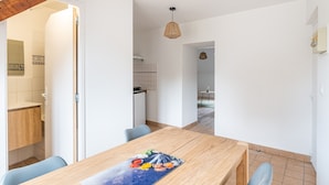 A modern kitchen with white cabinets, a wooden countertop, and a dining area with a wooden table and chairs. - Le Jaudy - Localisation idéale (Treguier)