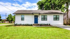 Una casa de un piso con puerta azul, revestimiento blanco y el número 800 a la derecha.
