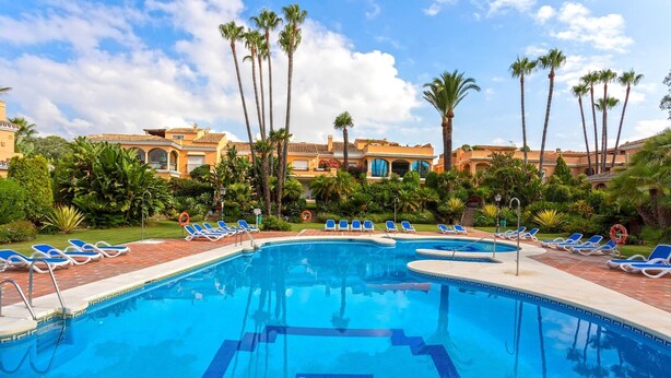 A swimming pool with blue water, surrounded by palm trees and lounge chairs. - Genteel Home Venalmar Terrace (Estepona)