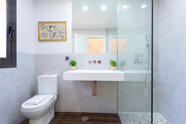 A modern bathroom with a toilet, a sink, and a glass-enclosed shower.