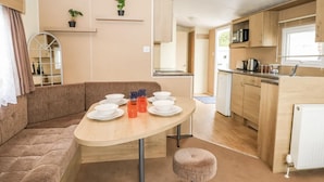A compact, modern RV kitchen with a dining area, wooden cabinets, and a small seating area. - Serene Chalet Retreat (Southampton)