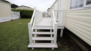 A white wooden staircase leading up to a deck area in a residential setting.