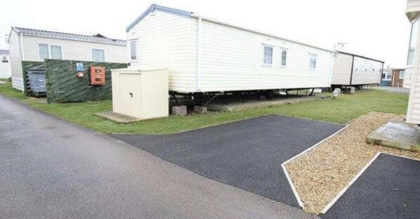A mobile home with a small attached garage, a paved driveway, and a grassy area. - Serene Chalet Retreat (Southampton)
