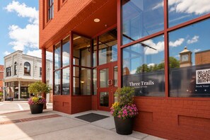 A building with large windows and a sign for 'Three Trails Boutique Loft Suites.'