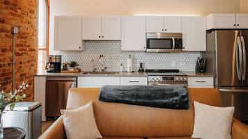 A kitchen with white cabinets, a stainless steel refrigerator, and a microwave.