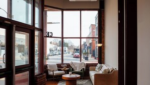 A cozy interior with a large window, a sofa, a chair, and a small table. - Three Trails Downtown Elkin (Elkin)