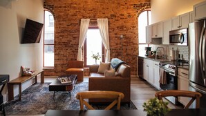 A modern kitchen with white cabinets, a stainless steel refrigerator, and a microwave. - Three Trails Downtown Elkin (Elkin)