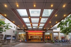 A hotel entrance with a glass canopy, a red-lit interior, and a staircase leading to the lobby. - Beichen Hotel (Haikou)