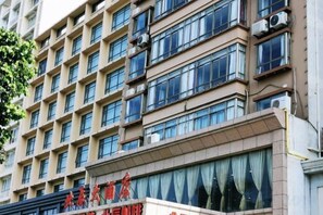 A multi-story hotel building with a series of windows and air conditioning units. - Beichen Hotel (Haikou)