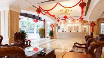 Vestíbulo de hotel con muebles de madera tradicionales, un mostrador de recepción y detalles decorativos en rojo.