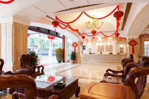 A hotel lobby with traditional wooden furniture, a reception desk, and red decorative elements. - Beichen Hotel (Haikou)