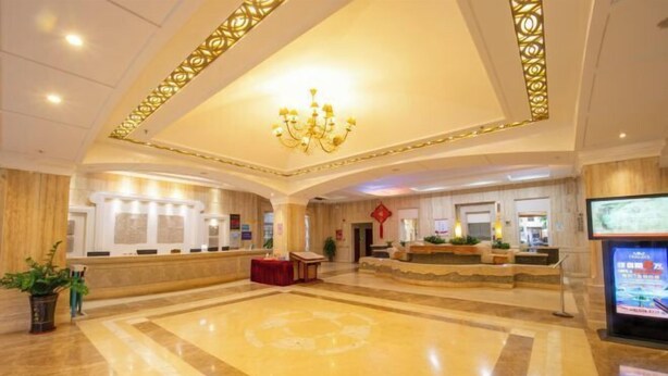 A spacious lobby with a reception desk, a chandelier, and a large screen displaying information. - Beichen Hotel (Haikou)